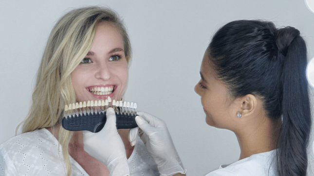 Shade guide held next to a client's teeth at The Smile Bar
