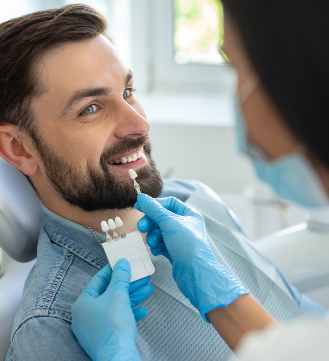 Dentist assessing tooth shade for veneer placement