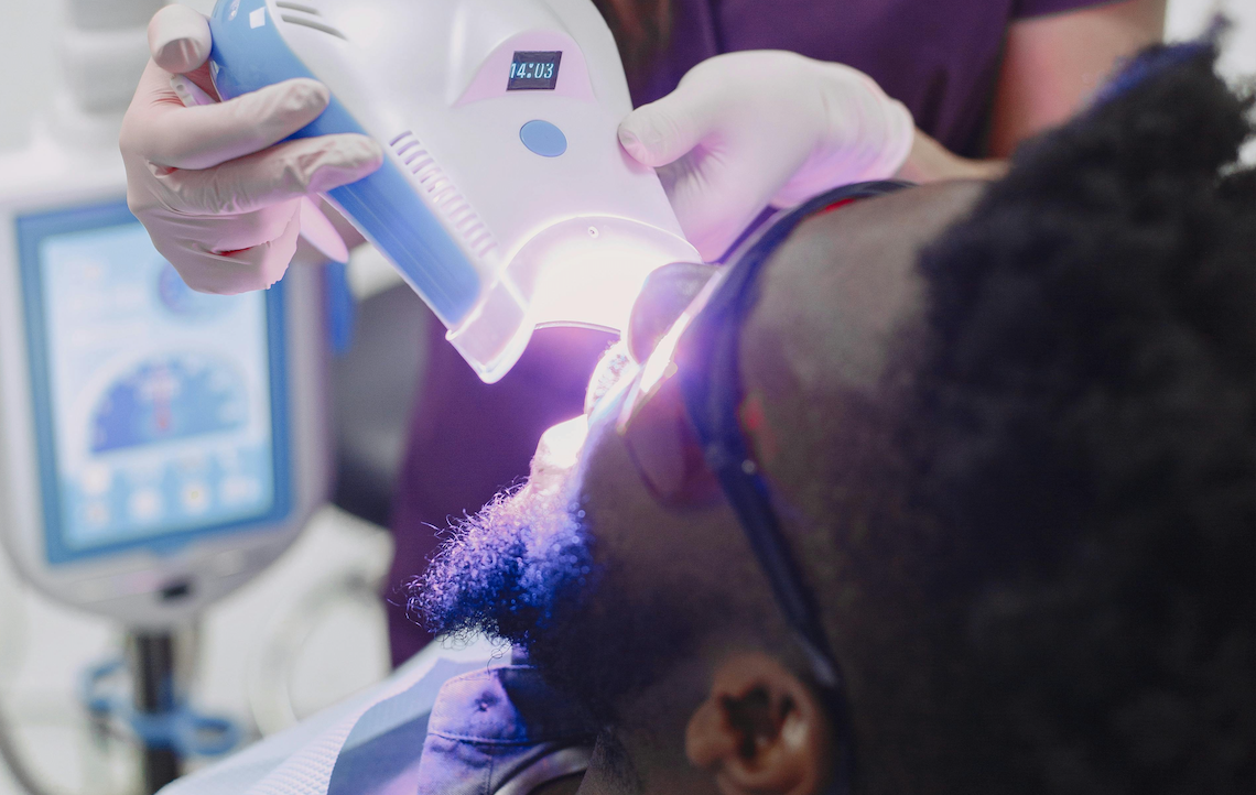 ทันตแพทย์กำลังใช้น้ำยาฟอกสีฟันเพื่อฟอกสีฟันให้ผู้ป่วยในคลินิก